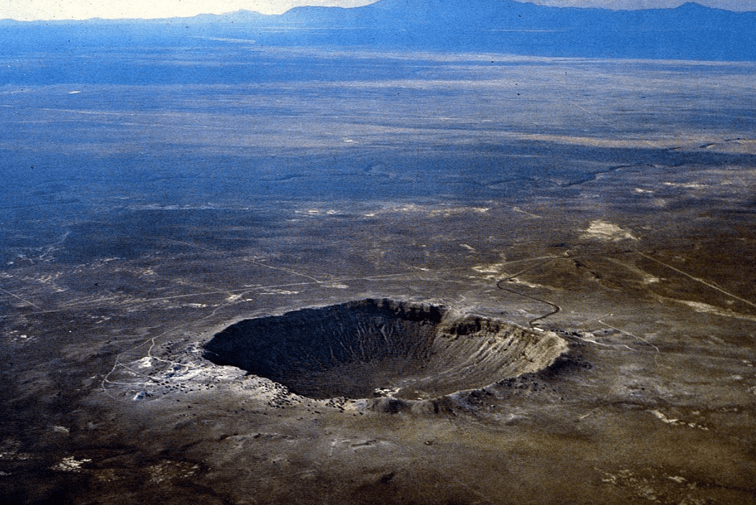 La imagen muestra una vista aérea de un gran cráter impactante, rodeado por la vasta y árida superficie terrestre, destacando su singularidad en el paisaje.
