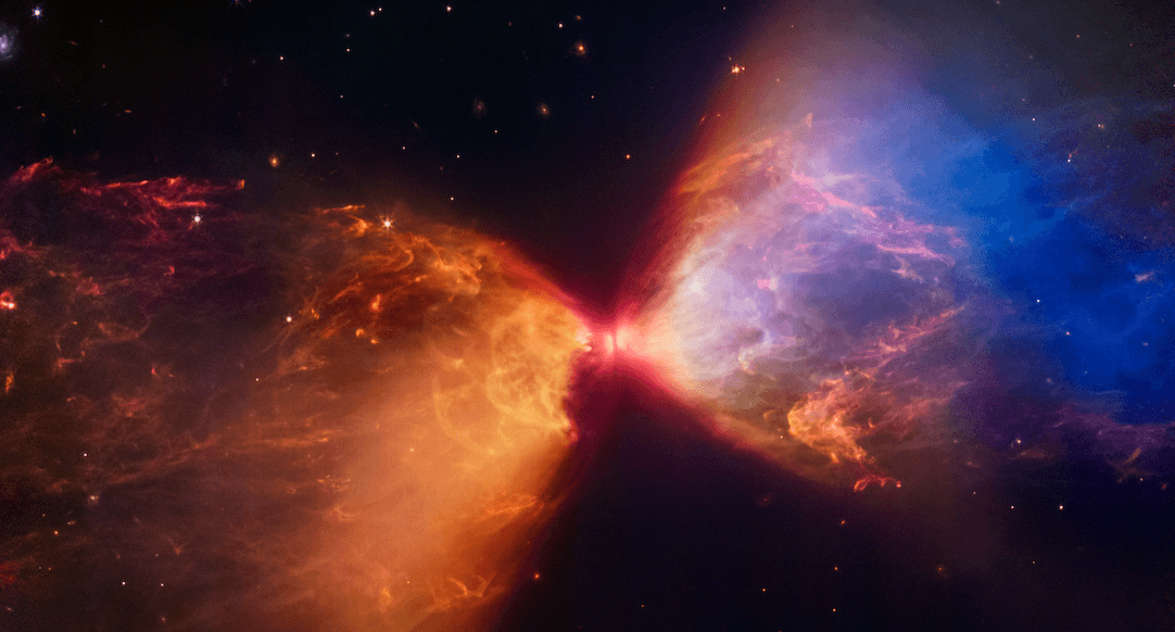 La imagen muestra una representación vívida de una nebulosa con colores intensos que varían entre rojos, amarillos y azules, destacando una zona central brillante y formas que sugieren la emisión de materia o energía.