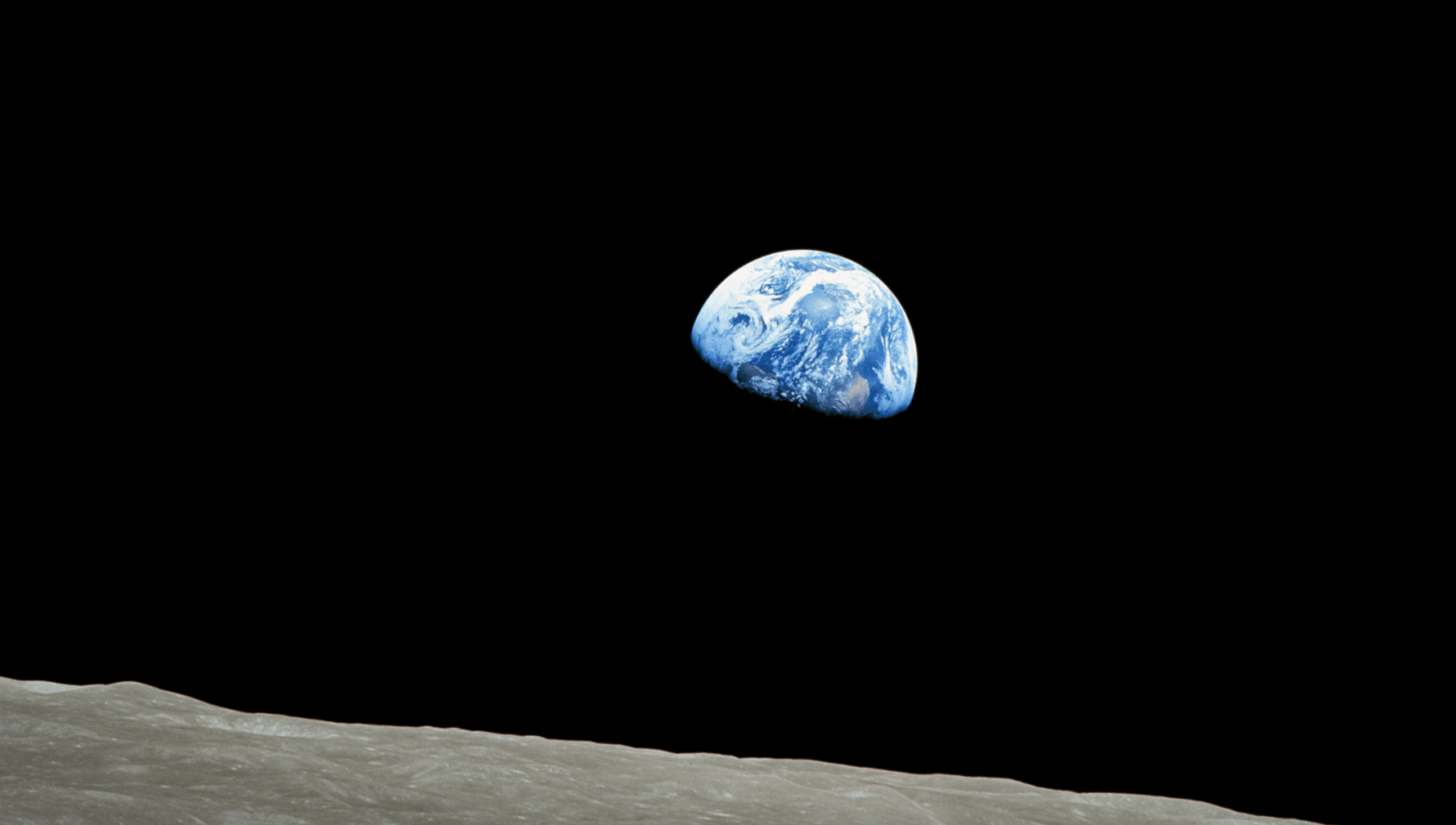 La imagen muestra una vista del planeta Tierra elevándose sobre el horizonte lunar, con el espacio negro como fondo. Esta perspectiva suele ser conocida como ‘amanecer de la Tierra’ desde la superficie de la Luna.
