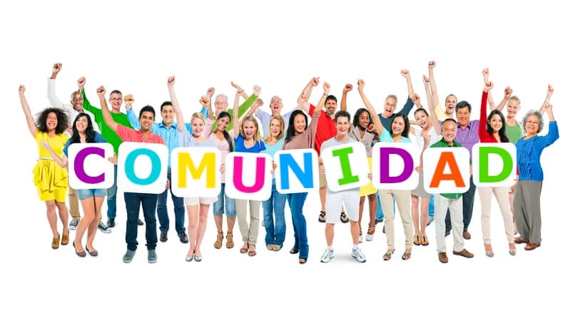 Un grupo diverso de personas entusiastas de diversas edades y etnias celebran con los brazos en alto mientras sostienen carteles con letras de colores que forman la palabra “COMUNIDAD” sobre un fondo blanco.